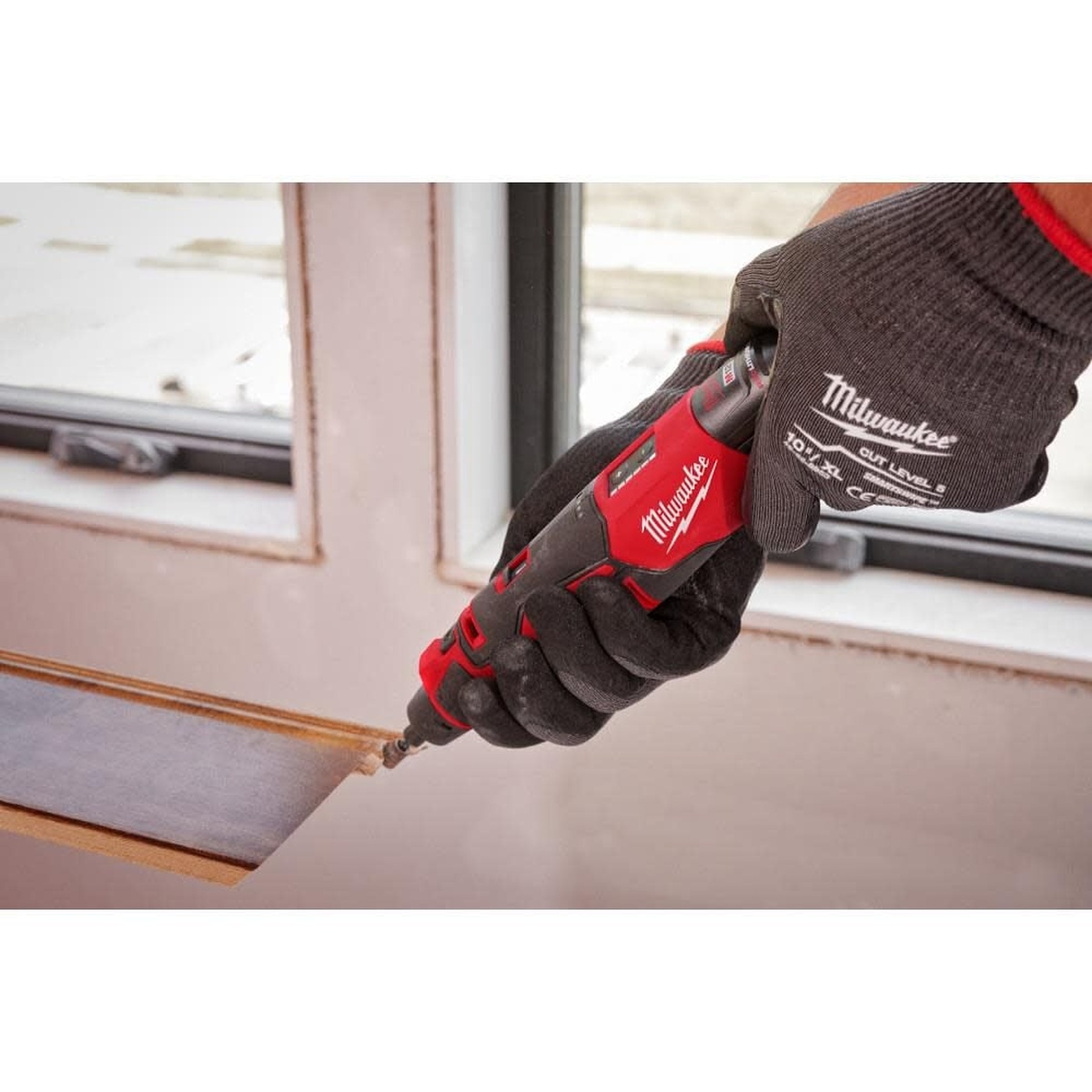 Milwaukee 2525-21 M12 Brushless Rotary Tool Kit trimming installed material near a window opening during finish work