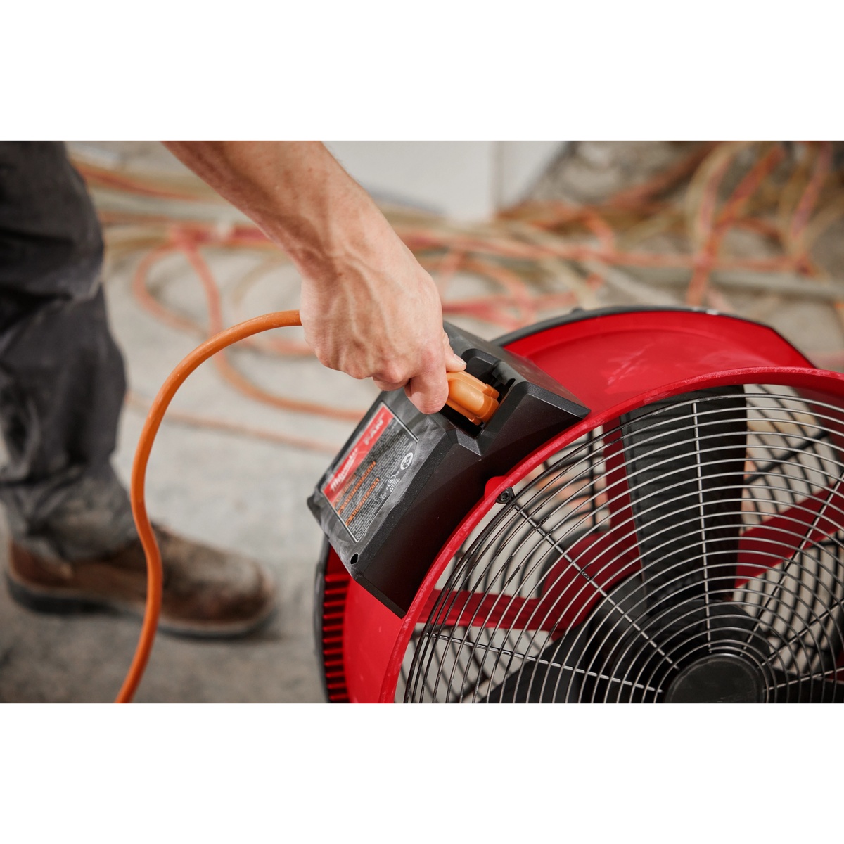 Milwaukee M18 Brushless 18 inch Fan connected to extension cord on a floor for extended runtime during indoor drying work