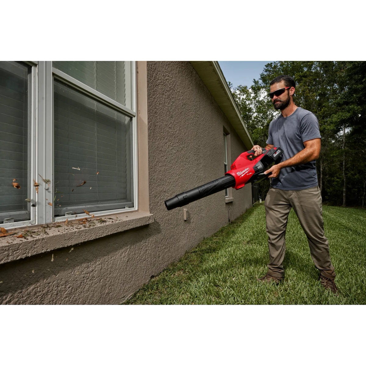Milwaukee 49-16-2797 Blower Tapered and Flat Nozzle Attachment Kit on a compatible blower pushing debris from a house window ledge and tight exterior edge