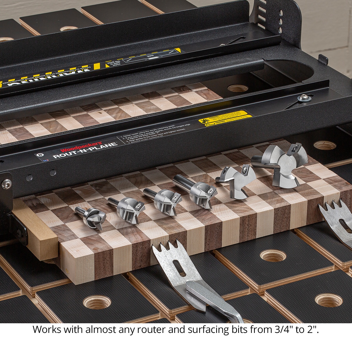 Woodpeckers Rout-N-Plane XL Bench Top Board Mill with multiple surfacing bits on a patterned cutting board in a woodworking shop