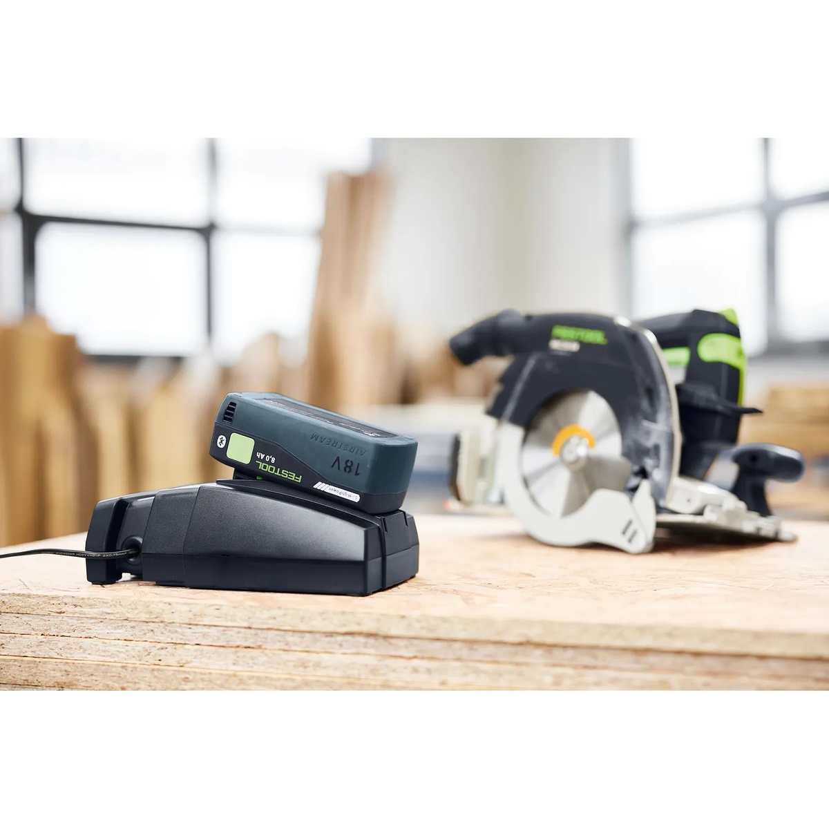 Festool 577328 SYS 18V Dual 8.0Ah and Dual SCA16 Fast Charger Energy Set battery charging on a workbench beside a cordless circular saw in a woodworking shop