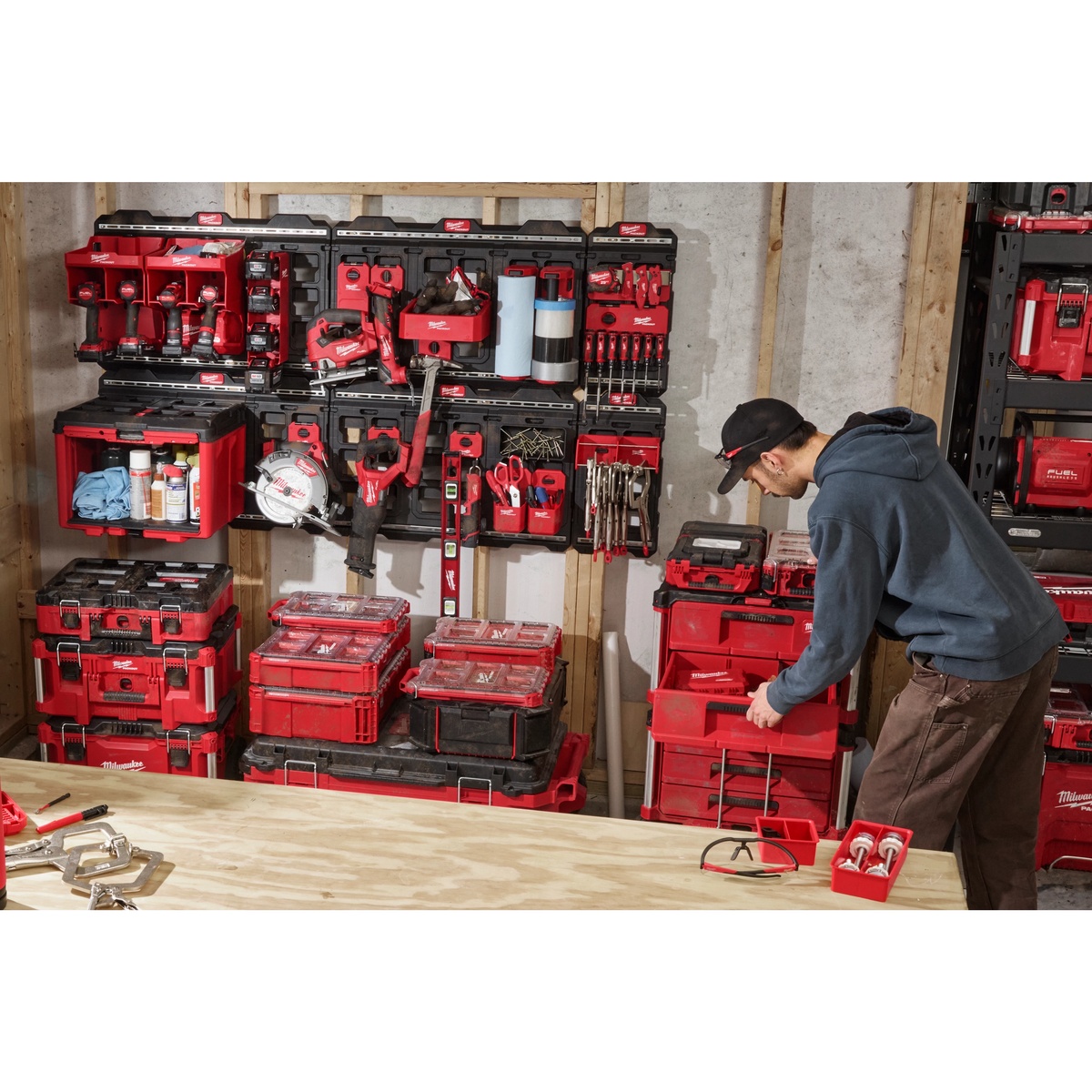 Milwaukee 48-22-8496 PACKOUT Compact Wall Plate used in a workshop wall storage setup holding PACKOUT organizers, tool holders, and accessories above a workbench