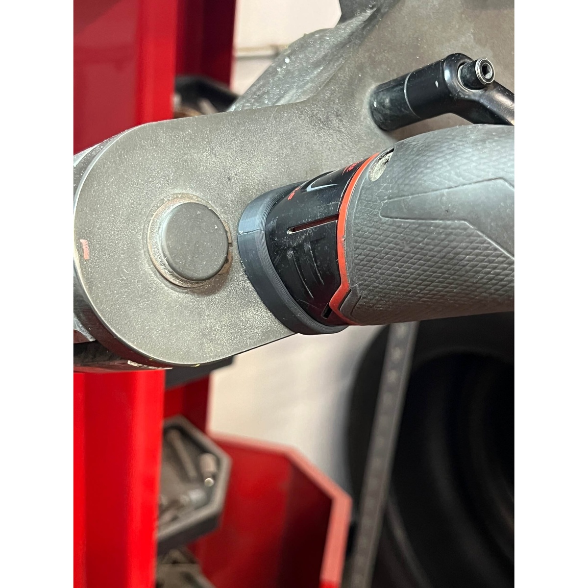STS Auto Design MW12TL Milwaukee M12 Tri-Lobe Magnet Battery Cover holding a Milwaukee M12 tool against a painted steel machine surface