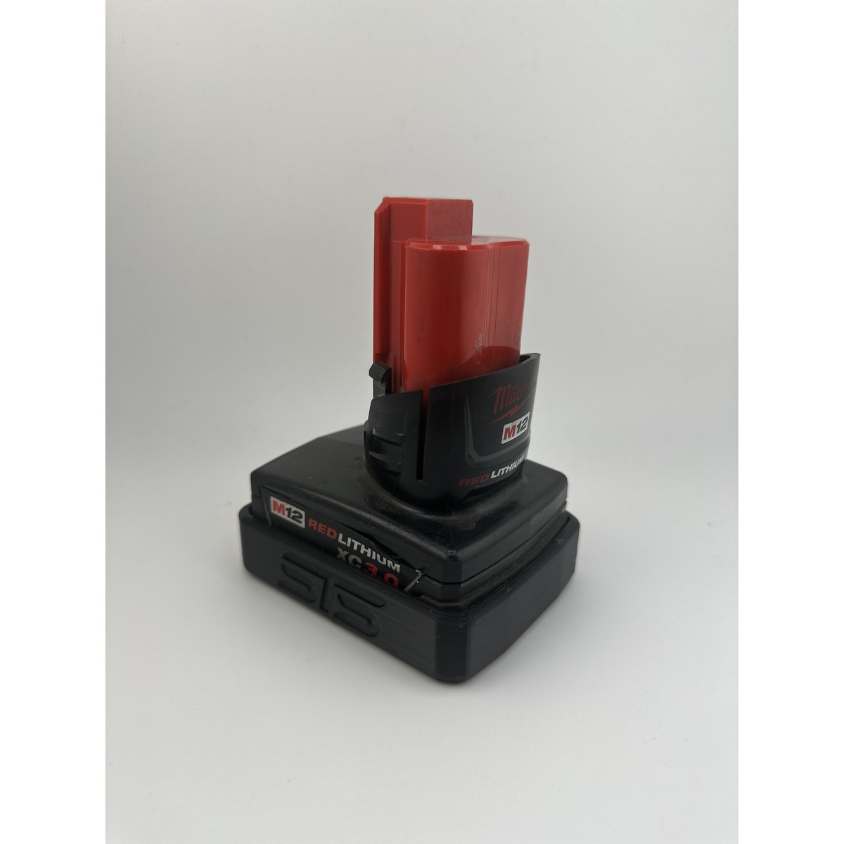 STS Auto Design MW12XC Milwaukee M12 XC Magnetic Battery Cover shown around an M12 XC battery from an angle highlighting the compact magnetic base and cover profile