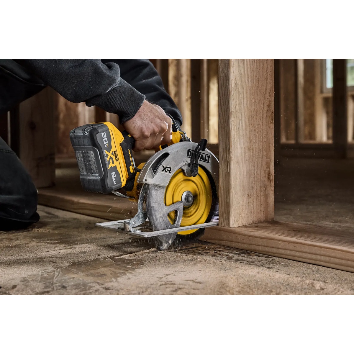 DEWALT DCS590B circular saw cutting wood framing material on a jobsite floor inside a framed structure
