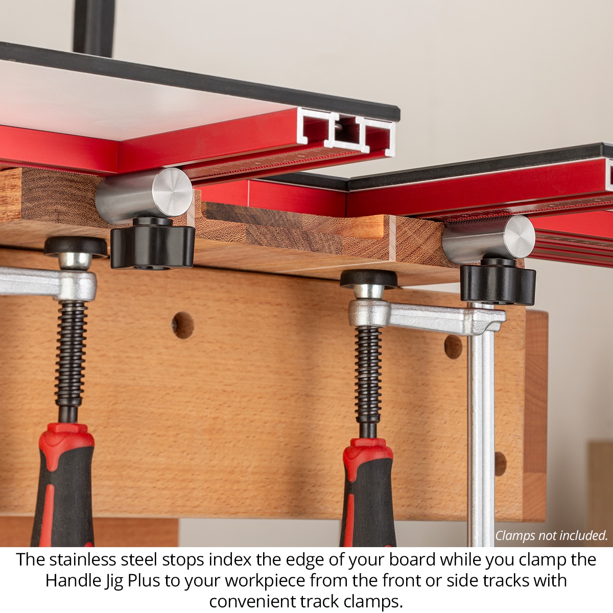 Woodpeckers Handle Jig Plus side view showing stainless steel stops indexing against the edge of a wood board and clamp tracks on a workbench
