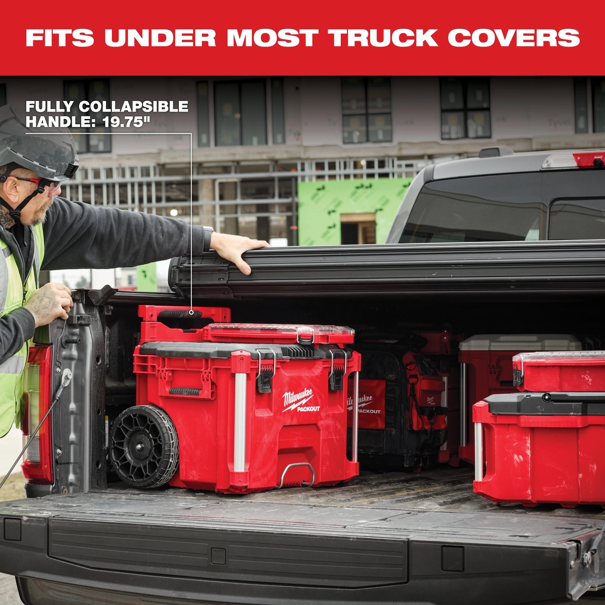 Milwaukee PACKOUT Rolling Tool Box 48-22-8427 stored under a full-size truck bed cover on an active construction site