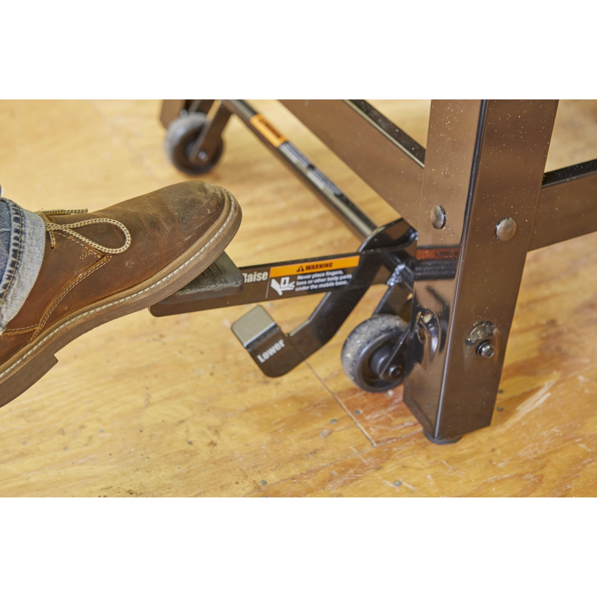 Close-up of a foot-operated mobile base under a SawStop contractor table saw in a woodworking shop for repositioning the saw around the workspace