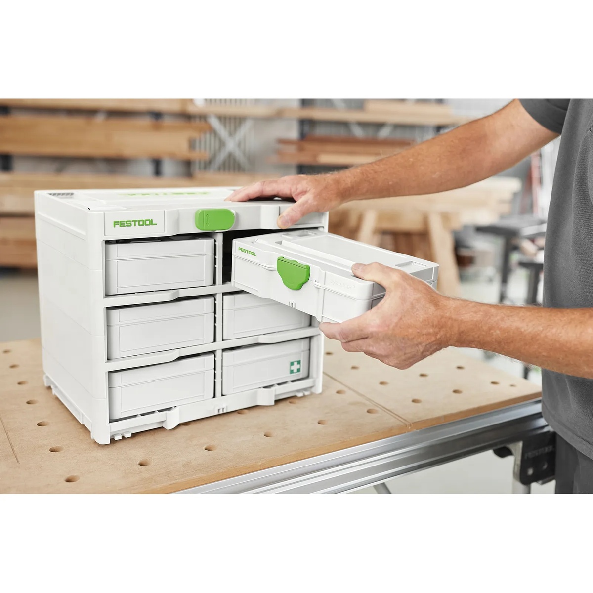 Festool 577807 SYS3-RACK 337 Systainer with a user removing a MINI-Systainer drawer from the rack at a perforated workbench