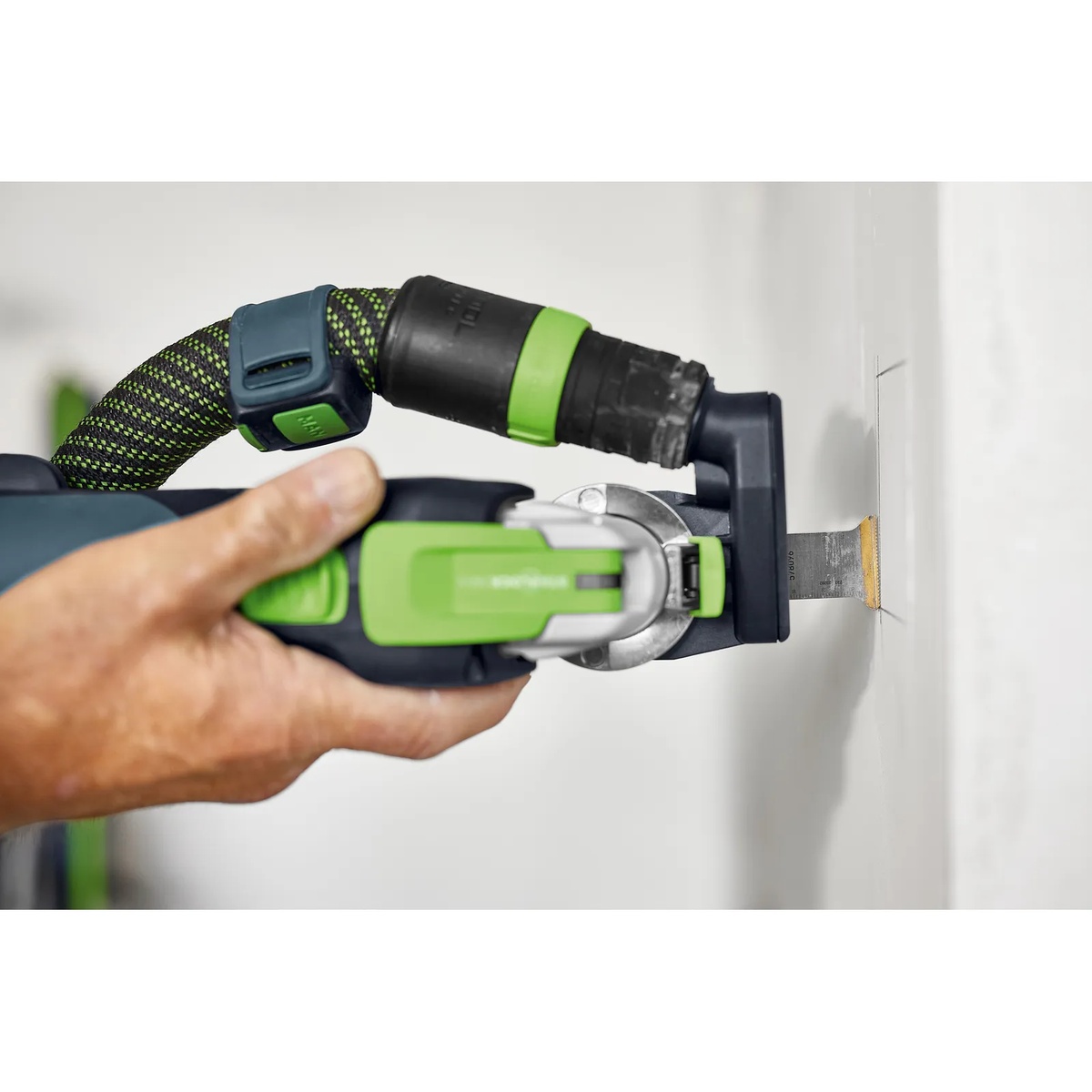 Festool 578096 MSB 60/32/HM/OSC 2-3/8 in. (60mm) x 1-1/4 in. (32mm) Carbide Blade (Starlock Plus) installed on an oscillating multi-tool making a plunge cut in a wall during interior remodeling work