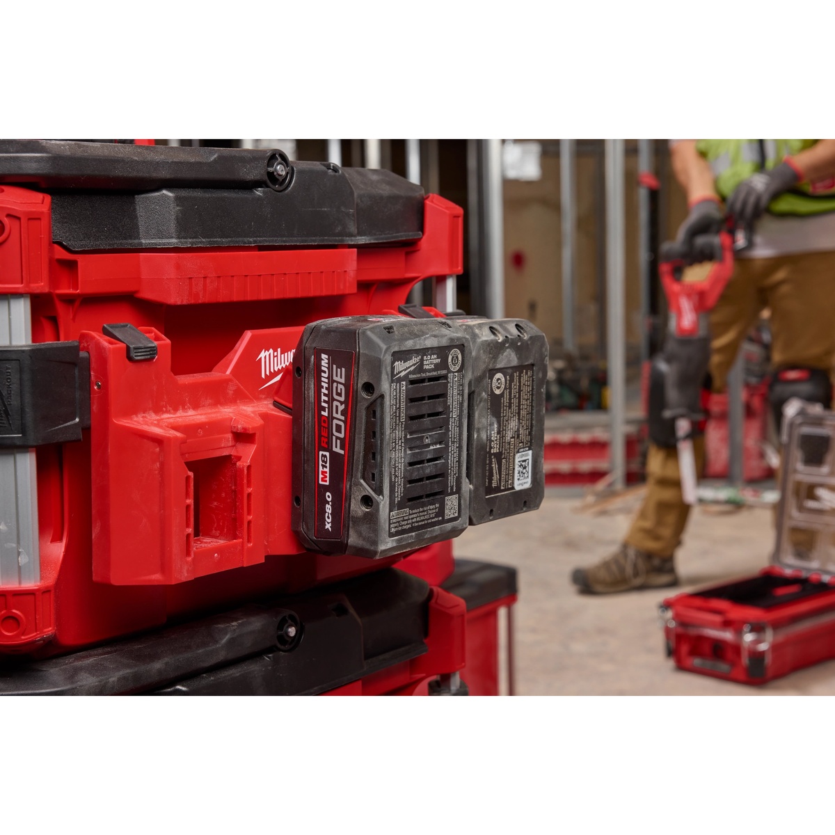 Milwaukee PACKOUT Tool Box M18 Battery Rack Attachment mounted on a PACKOUT tool box holding M18 batteries on an active indoor jobsite