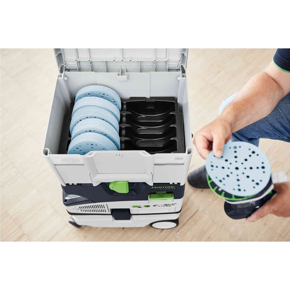 Festool D150 60-Piece 6-in. Granat Abrasives Holiday Value Starter Set with Systainer3 SYS-STF stacked on a Festool dust extractor with a user grabbing a 6-inch sanding disc during shop sanding setup