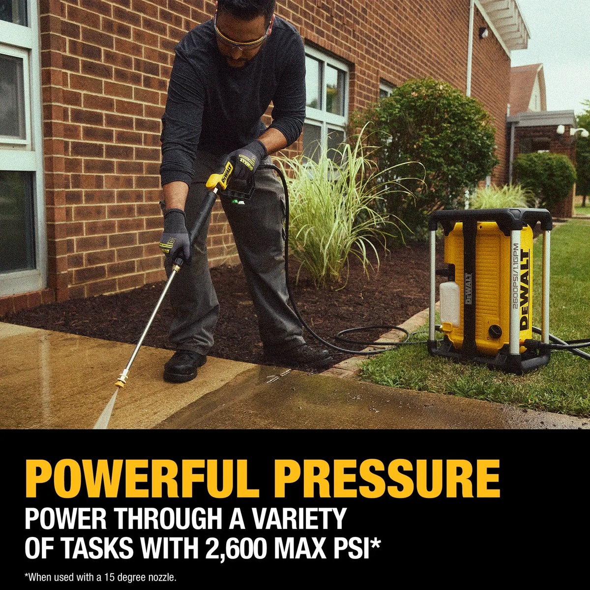 DeWALT DWPW2600 Electric Jobsite Pressure Washer cleaning a concrete sidewalk outside a brick building during outdoor maintenance work