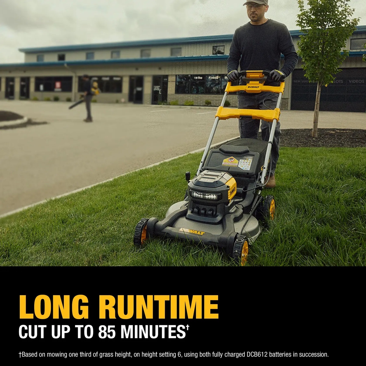 DEWALT 60V MAX 21-in. Brushless Cordless RWD Self-Propelled Lawn Mower Kit cutting residential grass near a commercial-style building during active mowing