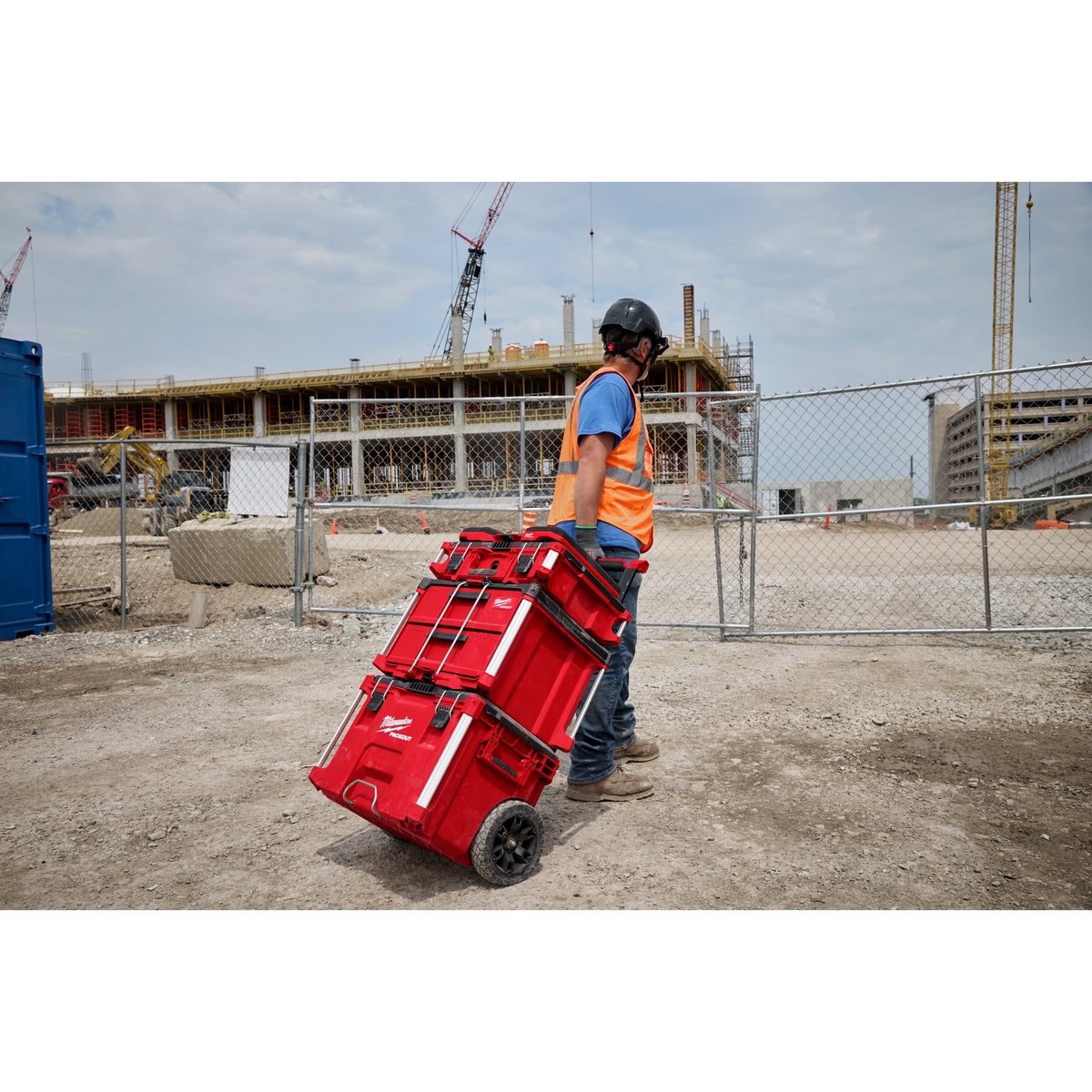 Milwaukee PACKOUT modular storage system being rolled across a construction site with the kneeling pad integrated into the setup