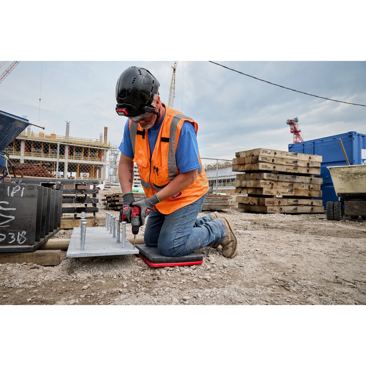 Milwaukee 48-73-6110 PACKOUT Kneeling Pad used on rocky ground while drilling anchors at an outdoor construction site