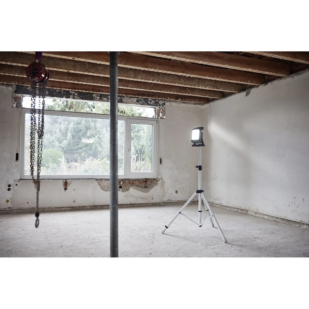 Festool 578126 SYSLITE KBS C Cordless 5000-Lumen Site LED Light mounted on a tripod lighting an unfinished remodel room for interior construction work