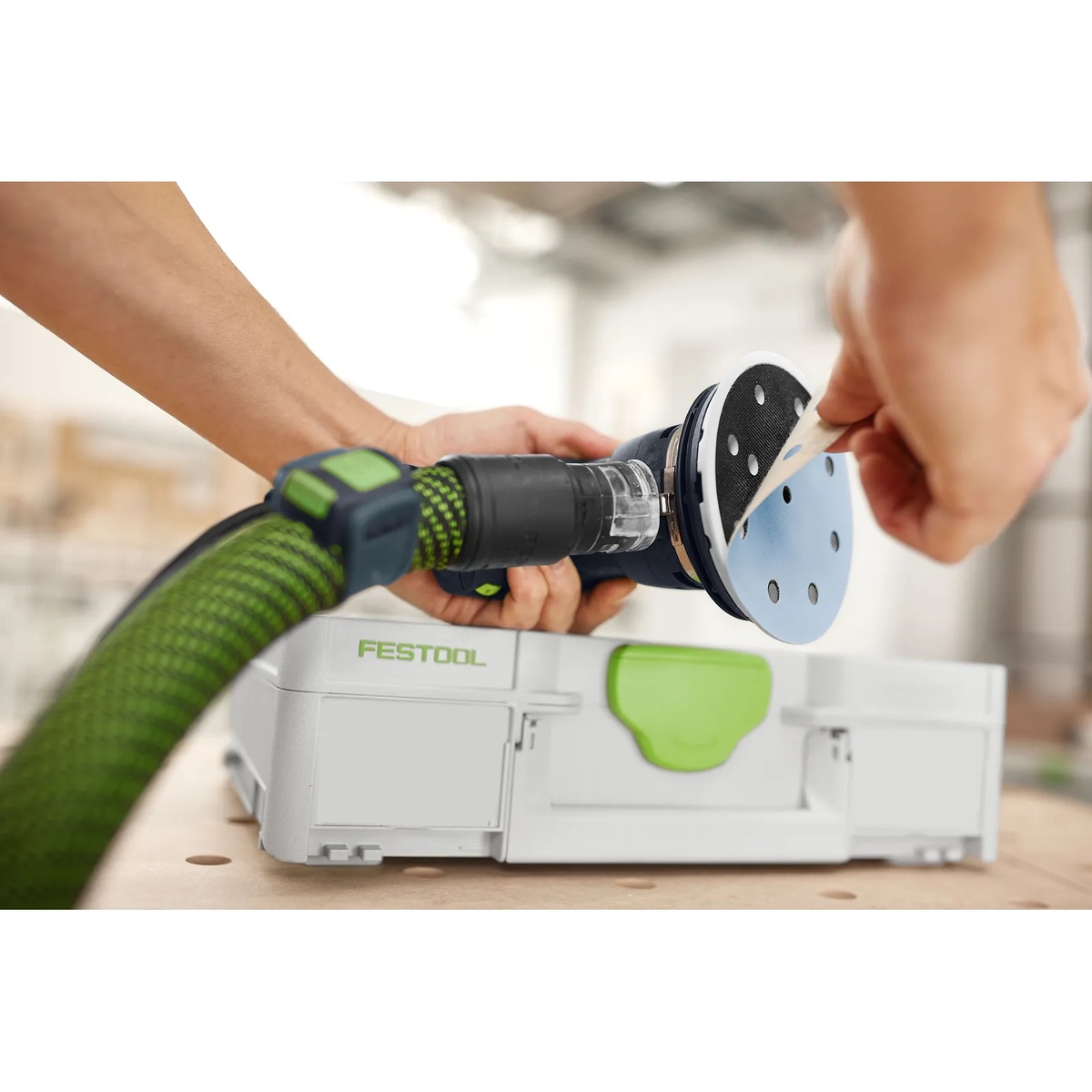 Festool Granat D125 sanding disc being applied to a Festool detail sander with dust extraction hose attached at a workbench