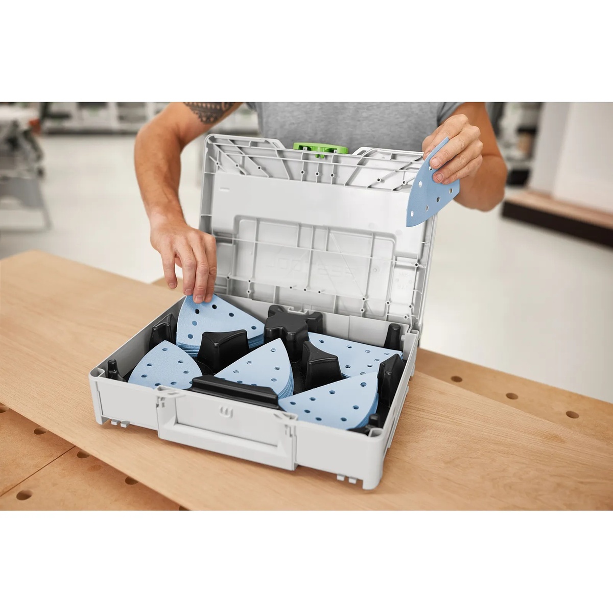 Festool 578195 Granat delta abrasive sheets being selected from the Systainer on a woodworking bench for paint prep and finish sanding work