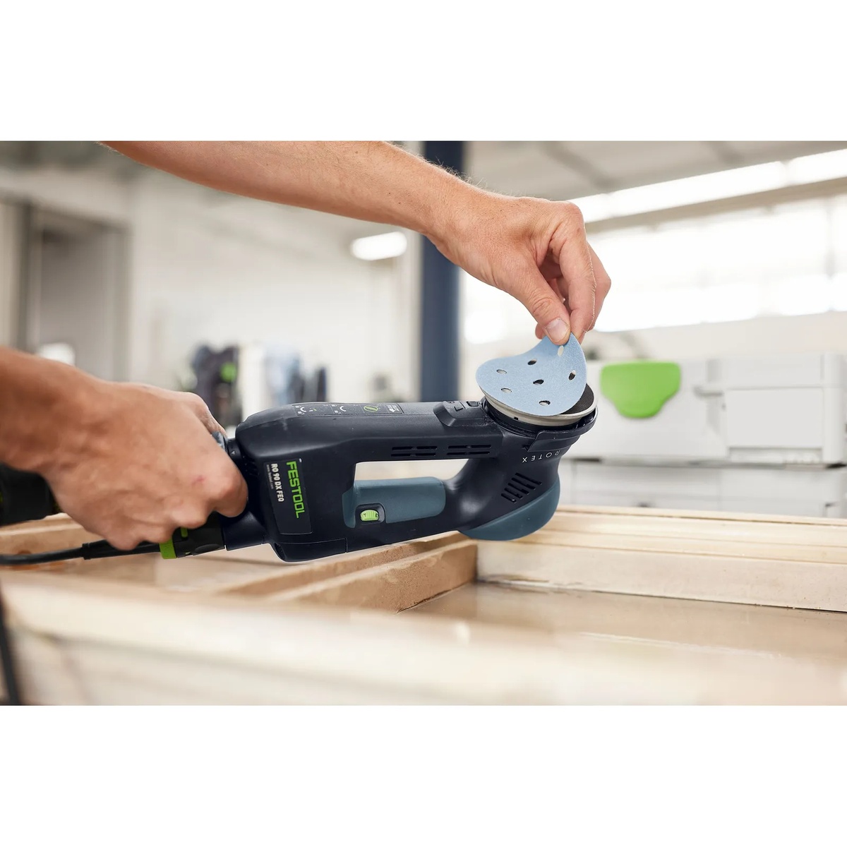 Festool 578196 Granat RO 90 / DX93 Abrasives D90 / V93 160-Piece Value Set Systainer3 delta abrasive being installed on a Festool RO 90 DX sander for detail sanding on wood at a workbench