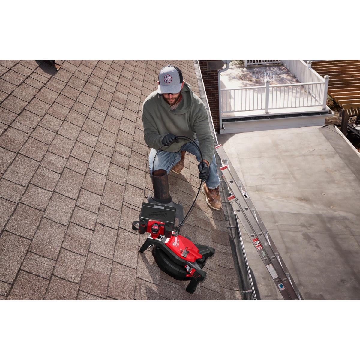 Milwaukee 3318-22B M12 85' High Flex Compact Inspection Camera Kit being used on a rooftop roof stack inspection with the reel set beside the access point