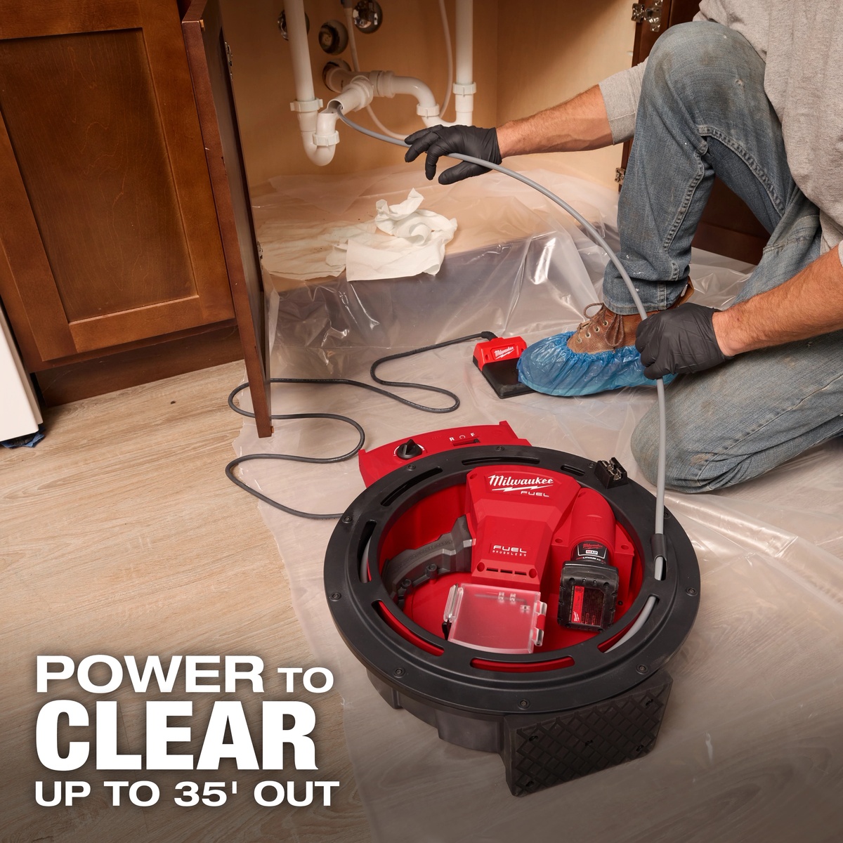 Milwaukee 2519-21 M12 FUEL High Speed Chain Snake clearing a branch drain under a sink in a residential cabinet during plumbing service work