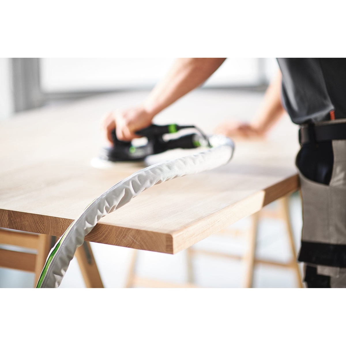 Festool ETS EC 150/5 EQ finish sander connected to dust extraction while sanding a hardwood tabletop in a workshop