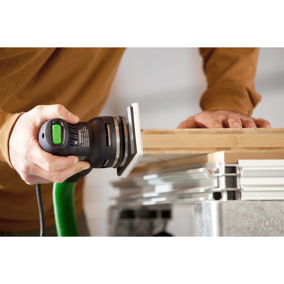 Festool RTS 400 REQ Orbital Sander Set w/ Granat Abrasive Value Set Systainer sanding the edge of a wood panel on a workbench during finish prep