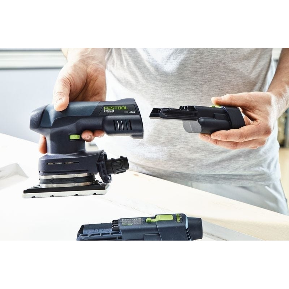 Festool RTSC 400 18V Brushless Hybrid Sander Set w/ Granat Abrasive Value Set Systainer with an ERGO battery being installed during sanding setup on a workbench
