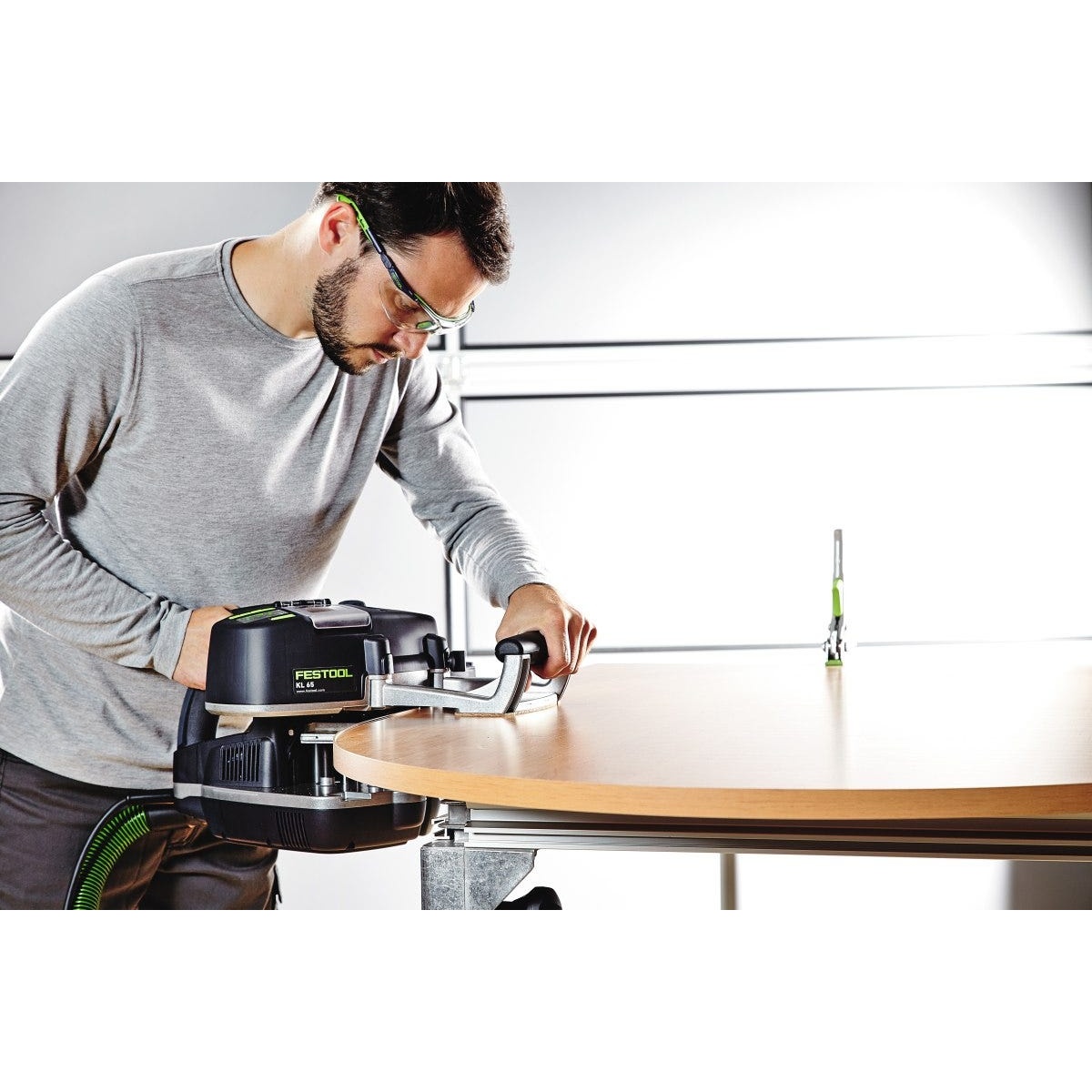 Festool 574616 Conturo KA 65 Edge Bander Deluxe Master Set applying edge banding along a curved wood tabletop in a workshop setting