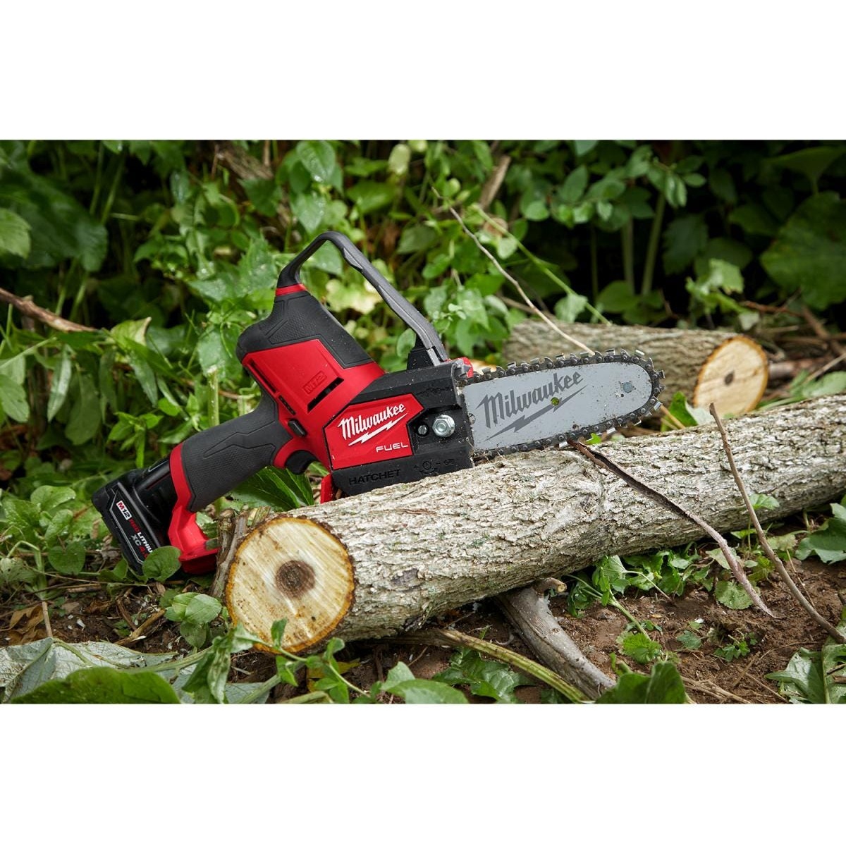 Milwaukee M12 FUEL HATCHET 6 inch Pruning Saw cutting a fallen tree limb on the ground during landscape cleanup