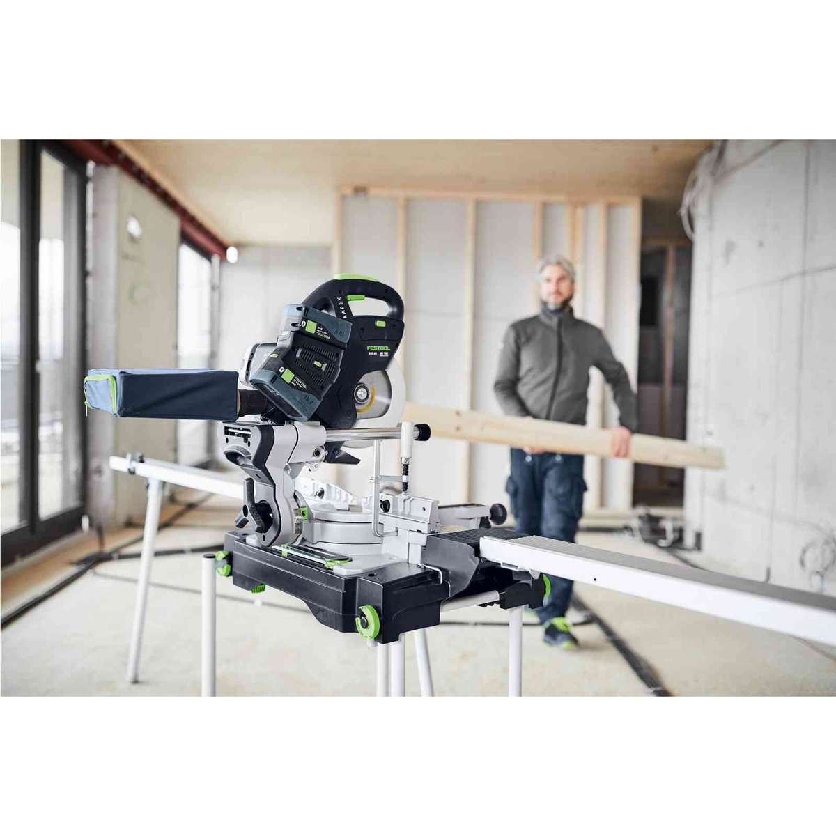Festool 577176 Kapex KSC 60 EB Cordless Dual-18V Miter Saw 5.0 Kit set up indoors with chip collection bag and long stock support for remodeling work