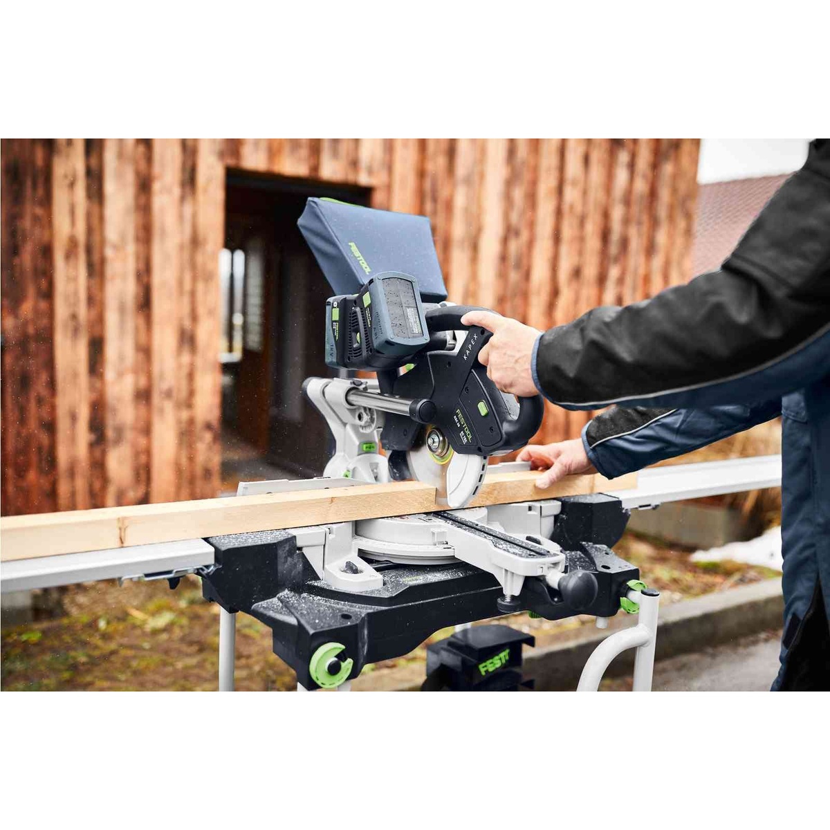Festool 577176 Kapex KSC 60 EB Cordless Dual-18V Miter Saw 5.0 Kit crosscutting lumber outdoors with dual batteries installed on the saw