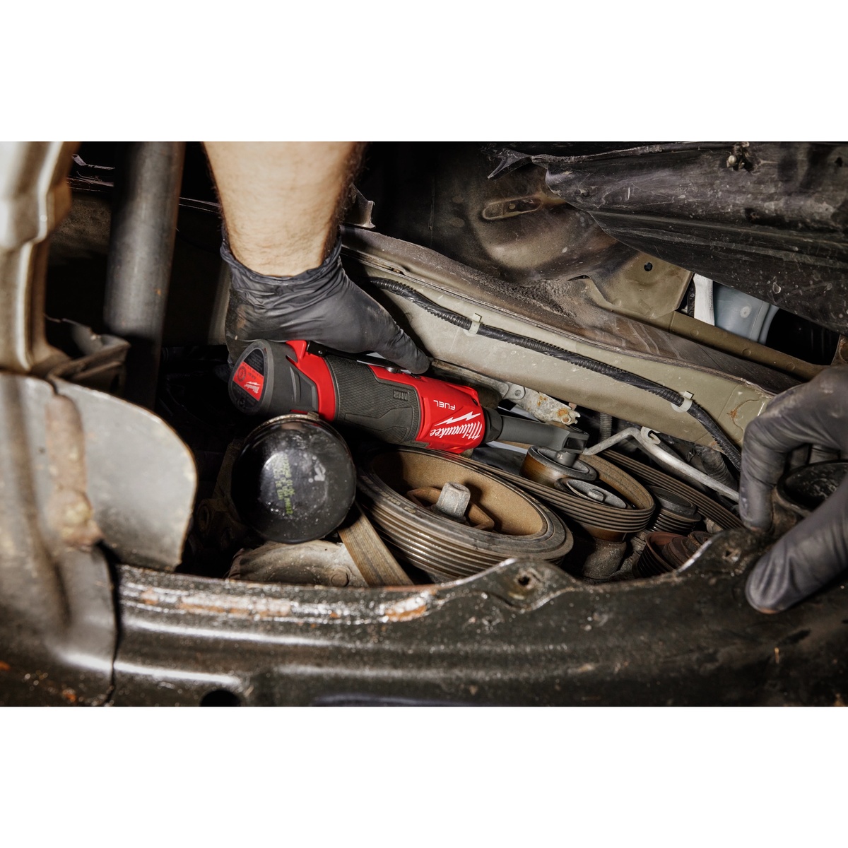 Milwaukee 3050-20 M12 FUEL INSIDER Extended Reach Box Ratchet working inside an engine bay on belt drive hardware in a tight automotive repair space