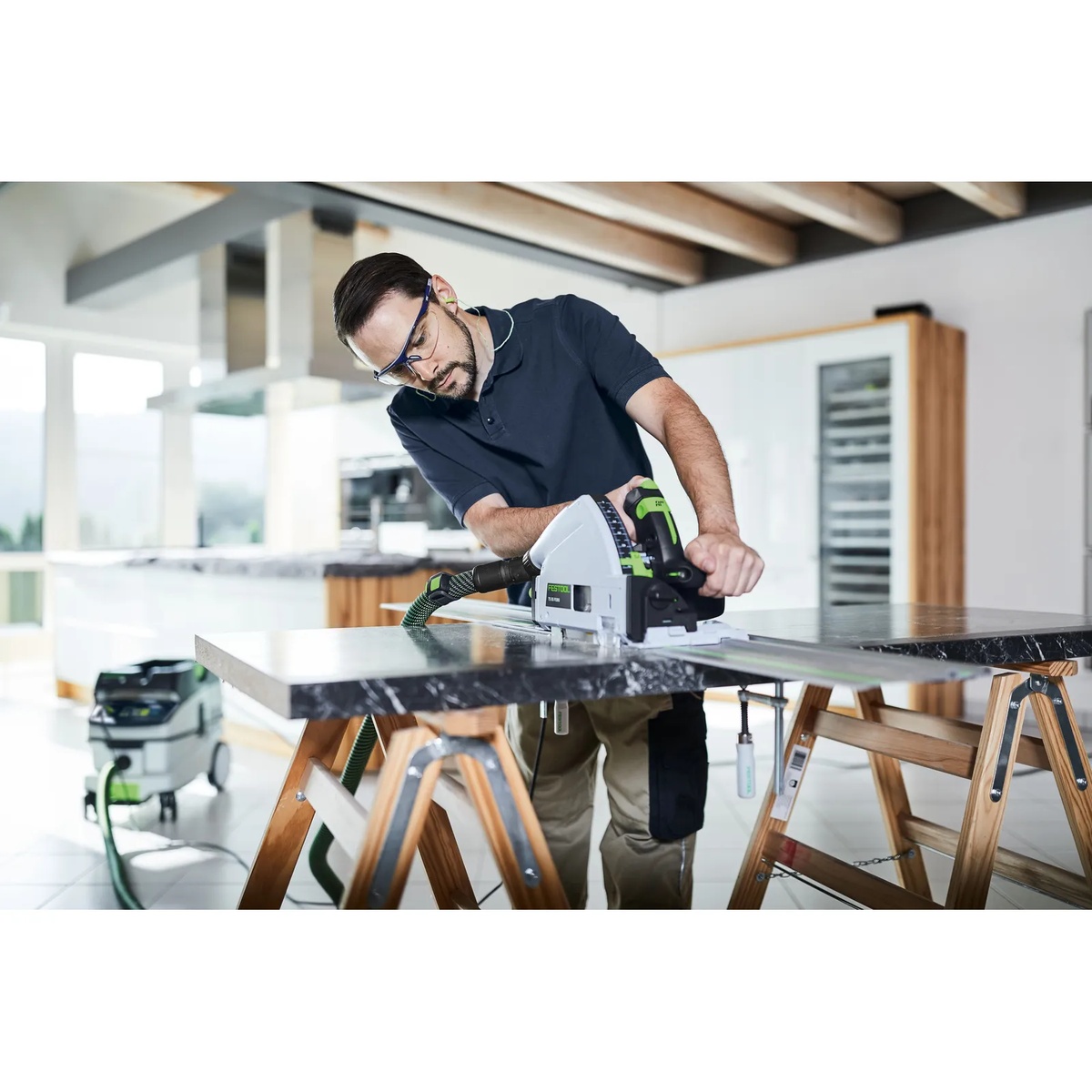 Festool 577871 CLEANTEC CT 26 EI HEPA Dust Extractor connected to a track saw while cutting a slab indoors on sawhorses during finish work
