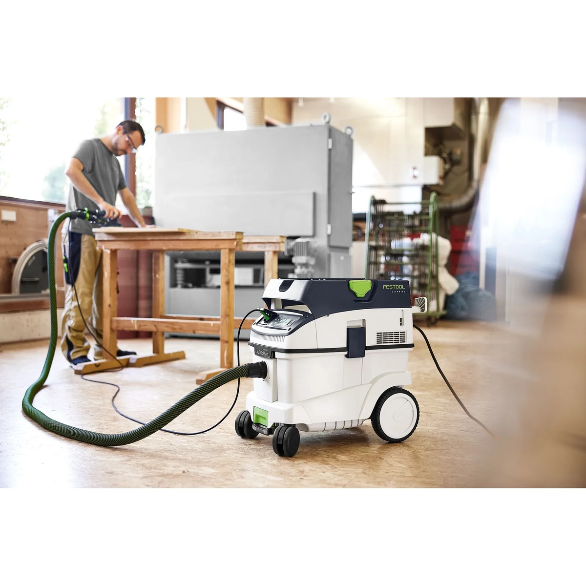 Festool 577874 CLEANTEC CT 36 EI AC AutoClean HEPA Bluetooth Dust Extractor collecting dust while a user sands wood in a workshop jobsite setting