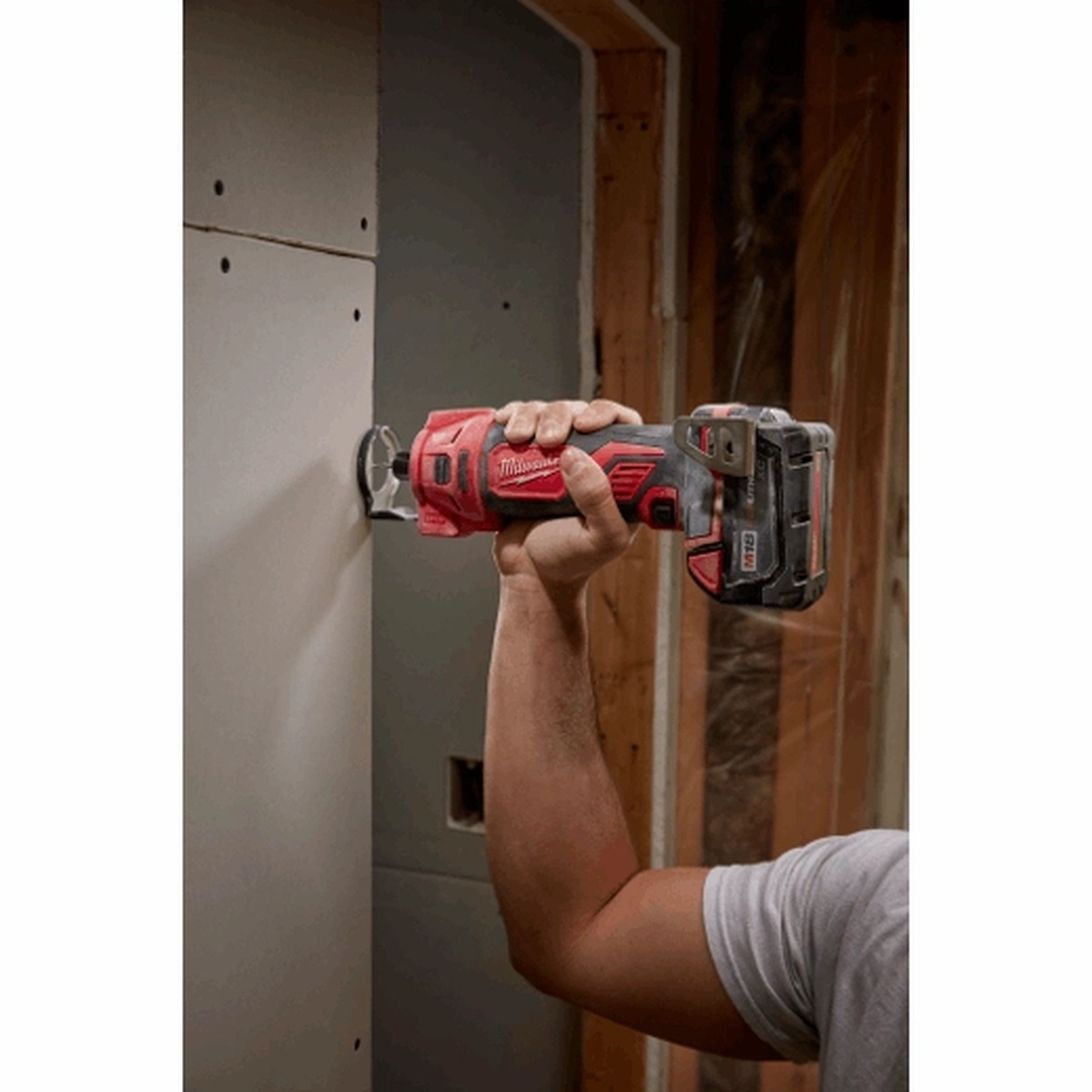 Milwaukee 2627-20 M18 Cut Out Tool trimming drywall around an opening with one-handed control in a framed interior room