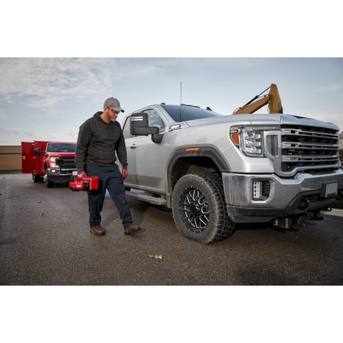Milwaukee M18 18V Cordless Tire Inflator carried beside a pickup truck on a jobsite for portable tire inflation work