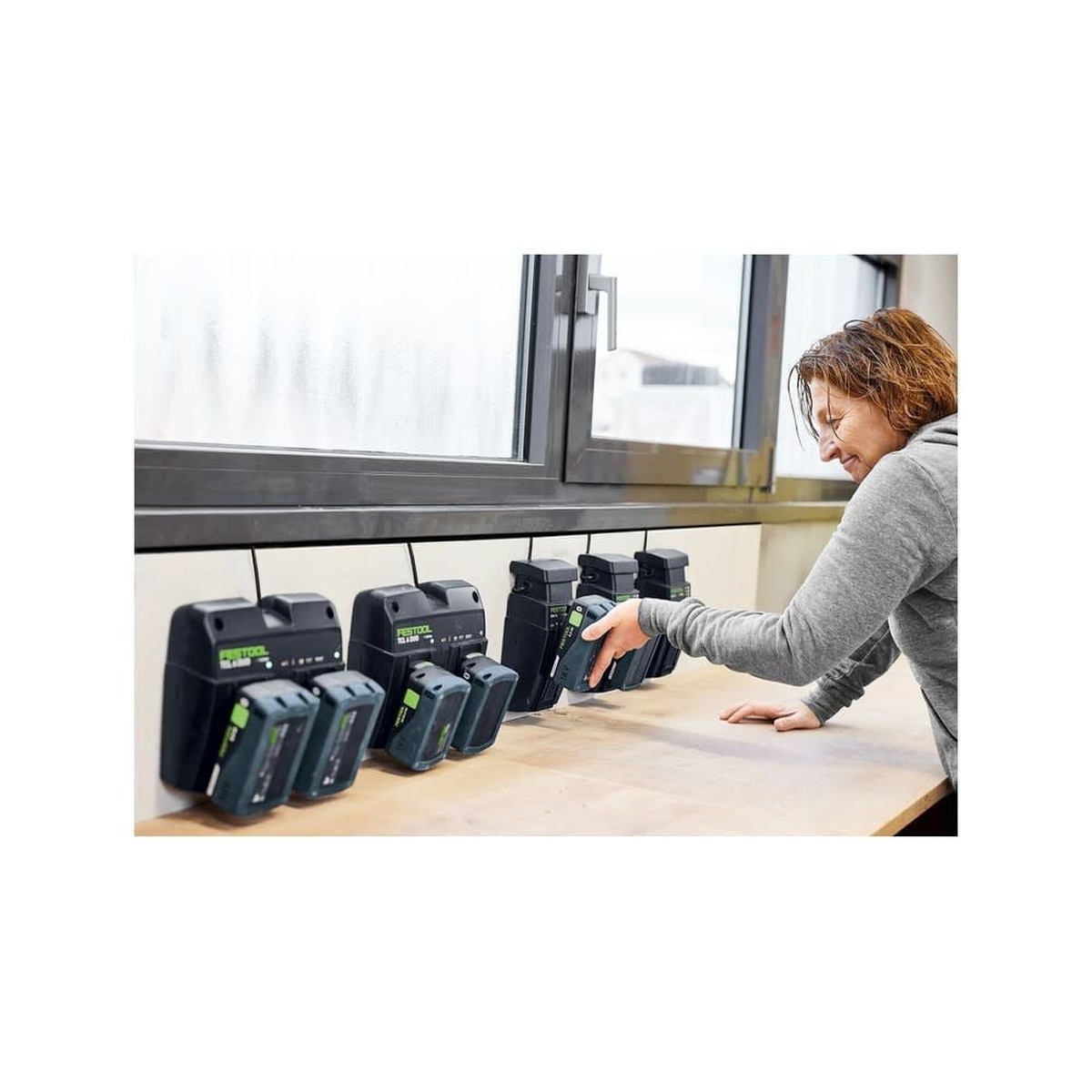 Festool 578201 Limited Edition 18V 5.0Ah Battery 4-Pack with chargers on a workbench, showing battery charging and swap-ready storage in a workshop setting