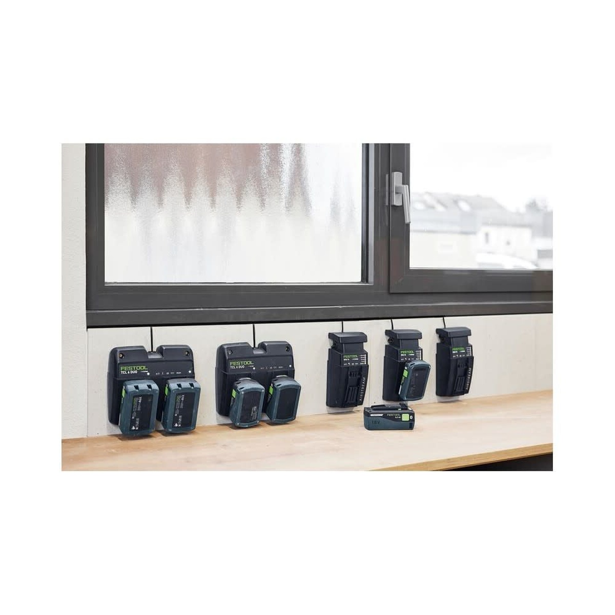 Festool 578201 Limited Edition 18V 5.0Ah Battery 4-Pack charging on multiple wall-mounted chargers in a workshop near a window