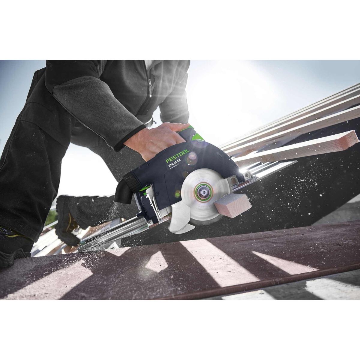 Festool 576173 HKC 55 Cordless Bluetooth 5.2Ah Track Saw PLUS-FSK making a guided cut through framing lumber on a jobsite rail system