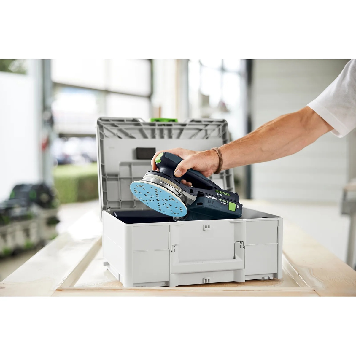 Festool ETSC 2 150 4,0 I-Plus cordless random orbit sander being lifted from a Systainer in a workshop for portable finish sanding on the job