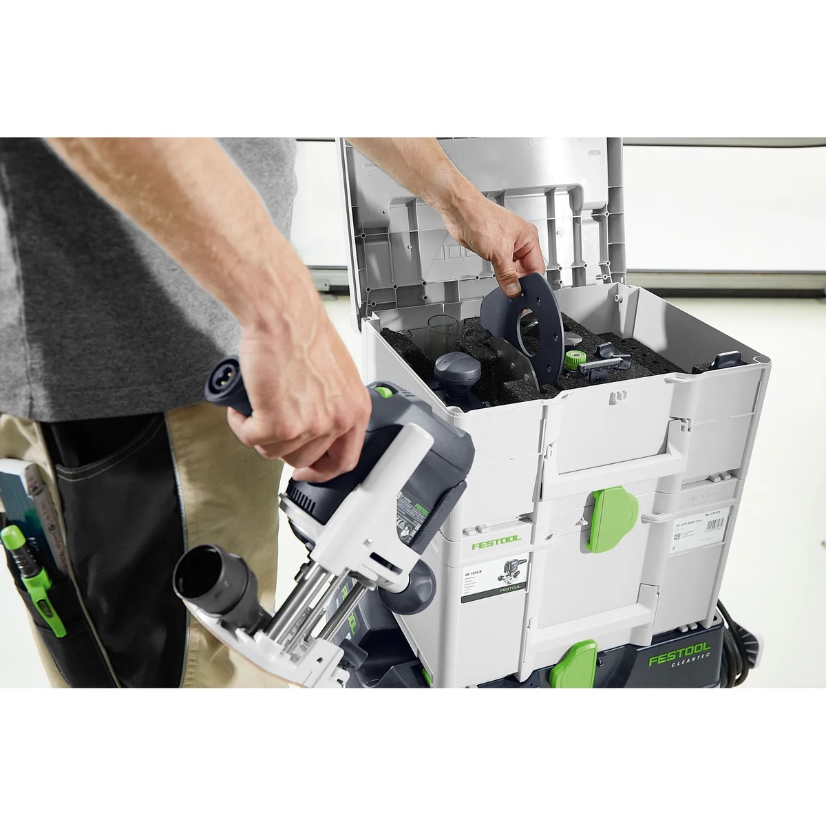 Festool 578047 ZS-OF 1010 I 17-Piece Imperial Router Accessory SYS3 Set being loaded beside a Festool OF 1010 router and dust extractor for organized transport and jobsite use