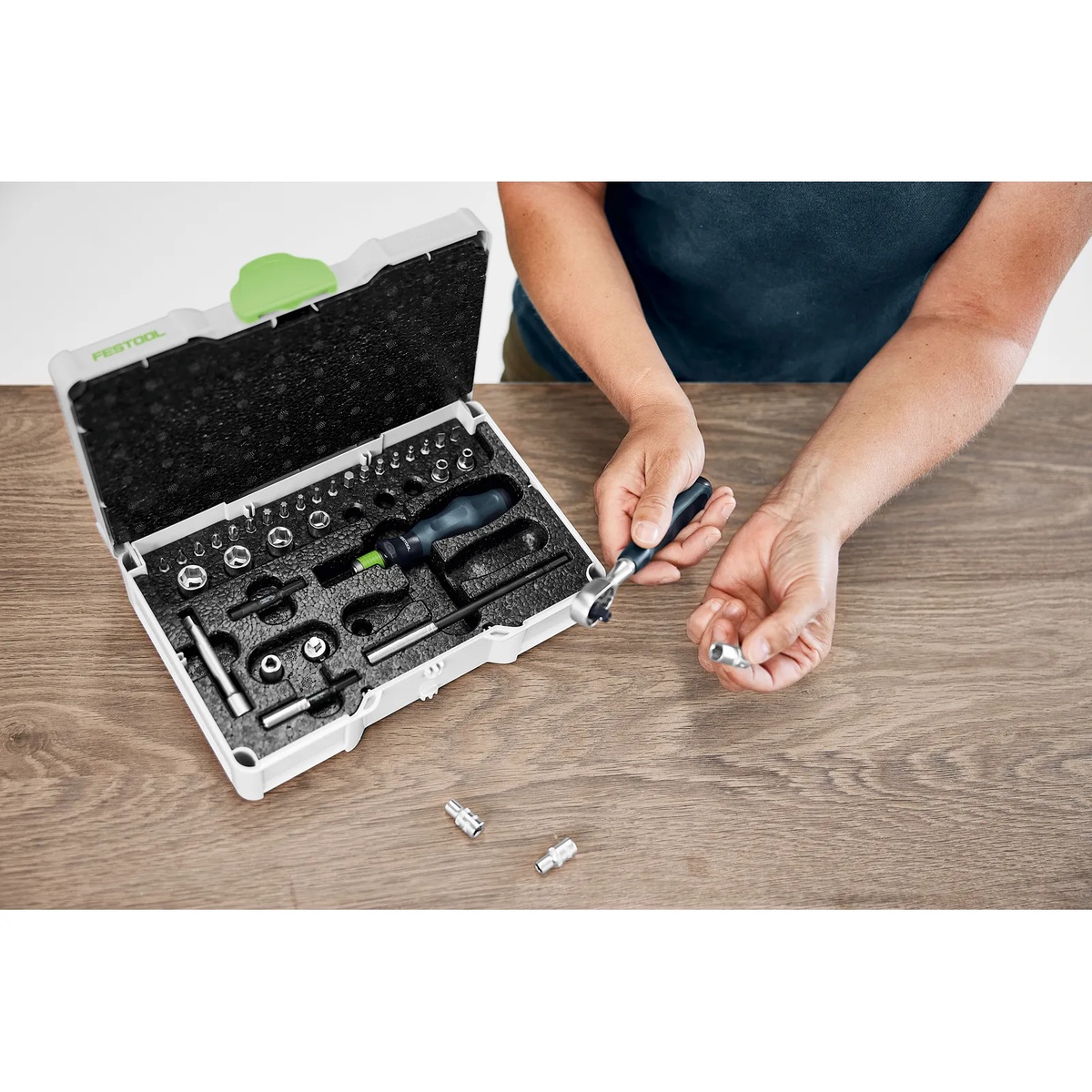 Festool 578112 Metric Ratchet and Socket Set SYS3 S 76-1/4-CE RA being used by hand at a worktable to fit a metric socket onto the ratchet during furniture or cabinet assembly