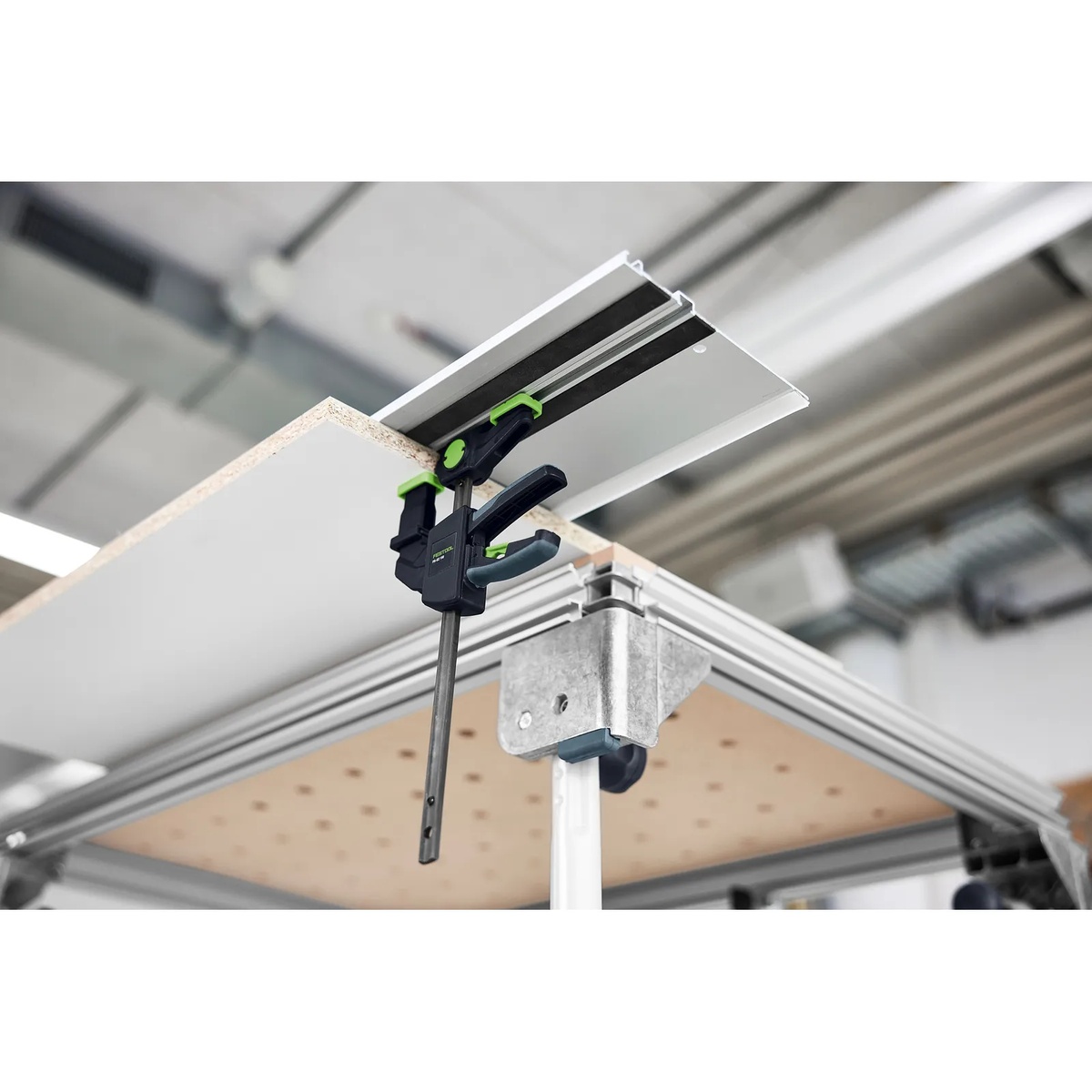 Festool FS-EZ 150/2 One-Handed Clamp attached under a guide rail and table setup holding sheet material in a workshop environment