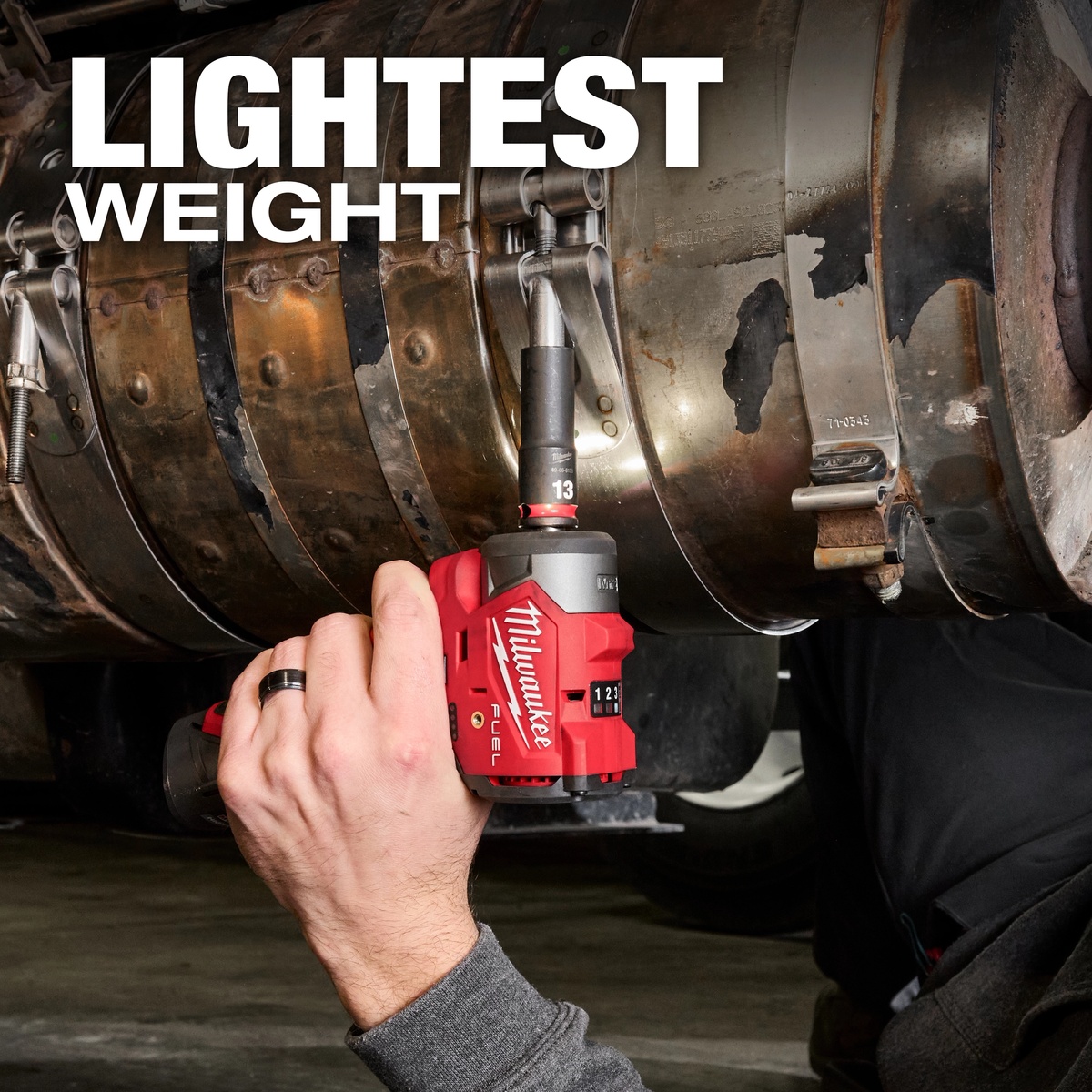 Milwaukee M12 FUEL 3/8 inch Subcompact Impact Wrench w/ Friction Ring being used overhead on a vehicle exhaust fastener in a shop