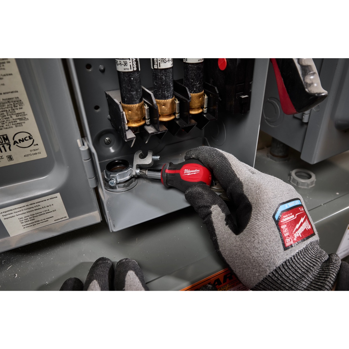 Milwaukee 48-22-2762 6-IN-1 Stubby Multi-Bit Screwdriver tightening hardware inside an electrical panel with gloved hand during service work