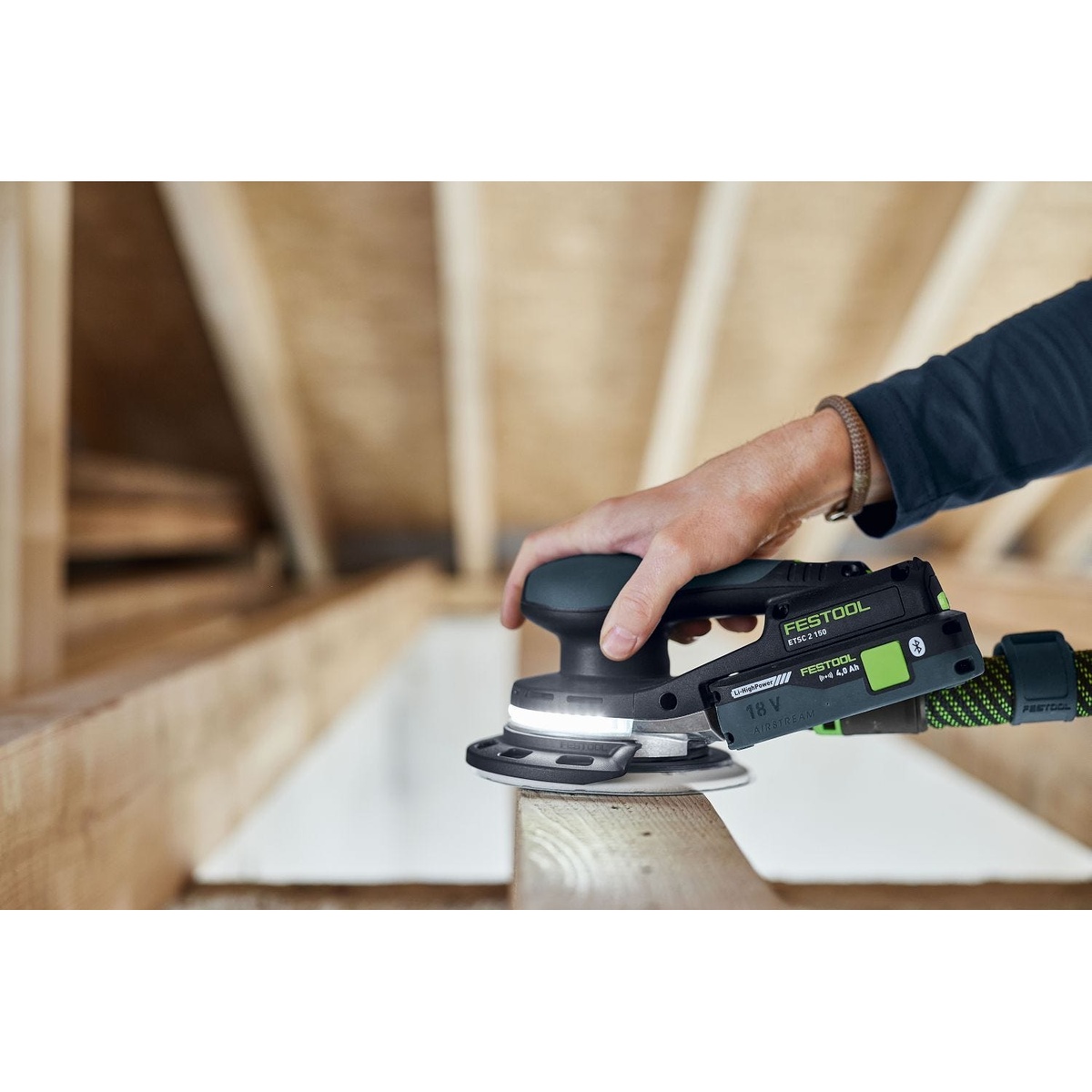 Festool Cordless 18V ETSC 2 150mm (6-in.) Sander Kit w/ 120-Piece GRANAT Abrasive Systainer Set sanding the edge of a wood member overhead in a tight interior workspace