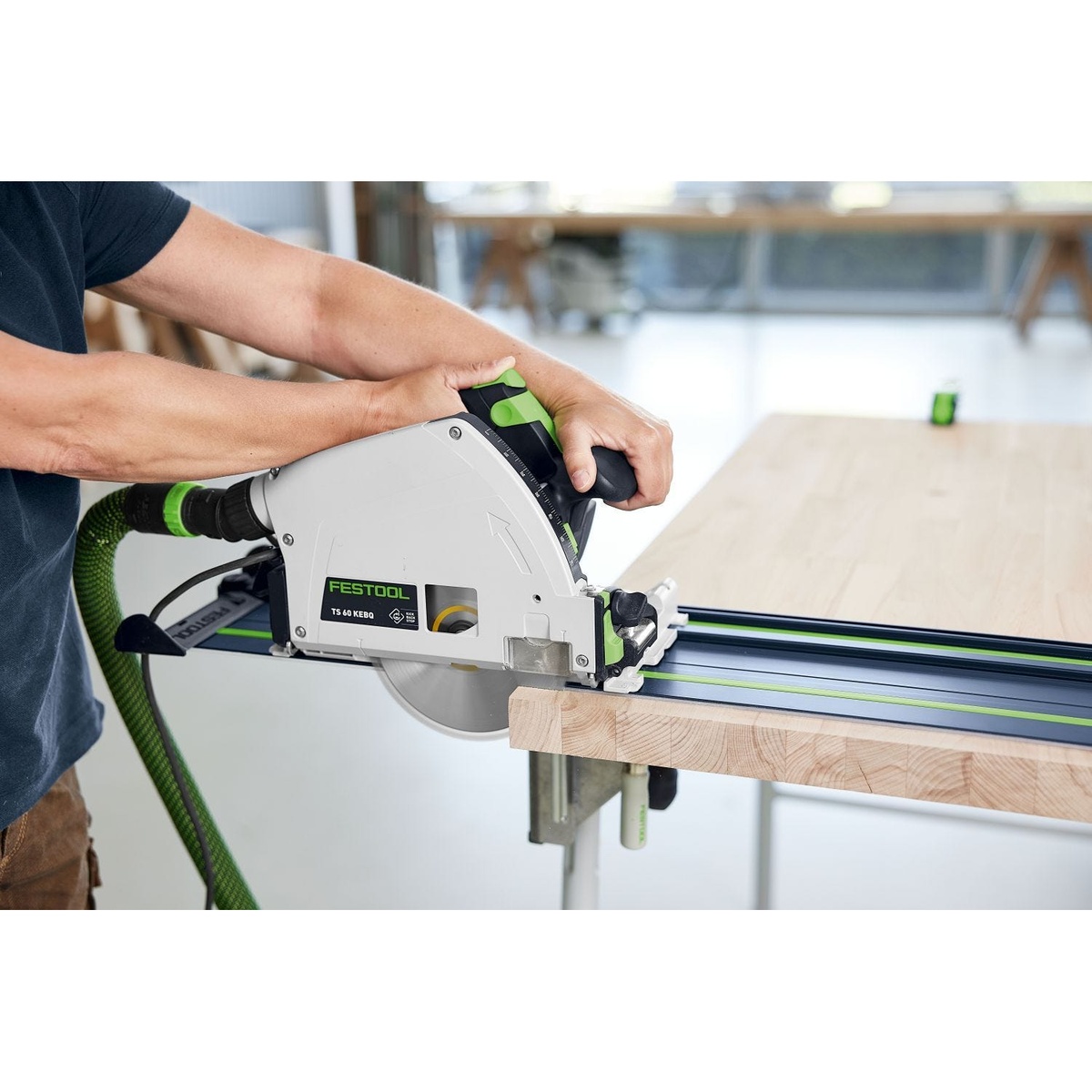 Festool Limited Edition Blue 55 inch Guide Rail 2-Pack w/ Rail Connectors and Tote Bag guiding a track saw through a wood panel on a workbench for straight sheet goods cutting