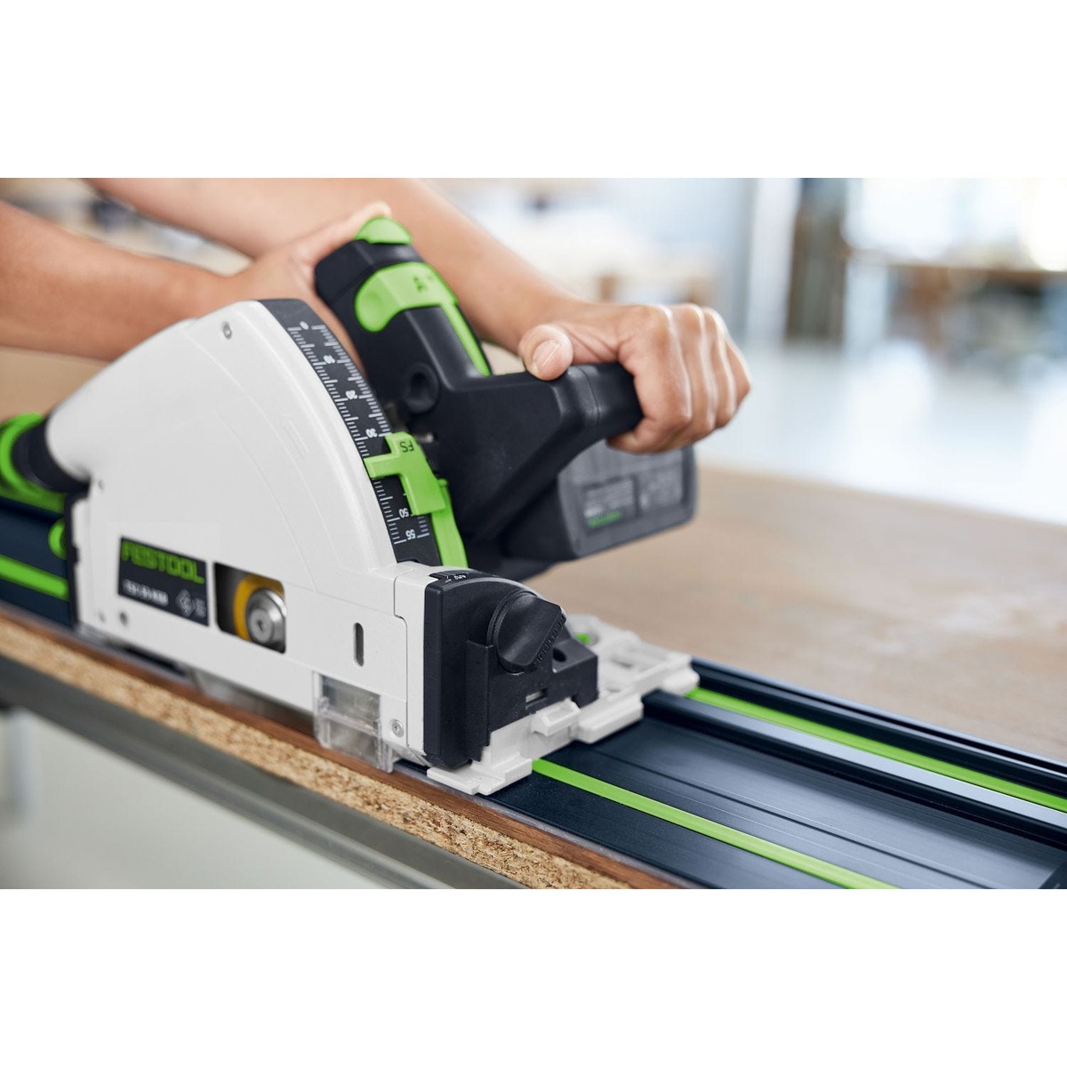Festool guide rail supporting a track saw during a precise panel cut on a bench top with the rail positioned on wood material